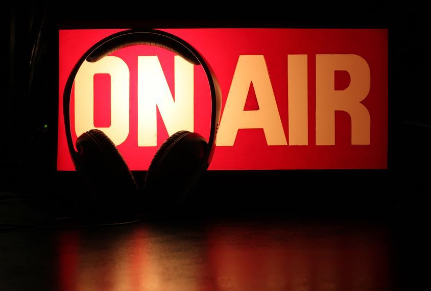 Cuffie davanti all'insegna On Air, simbolo della radiocronaca di Radio Touring 104