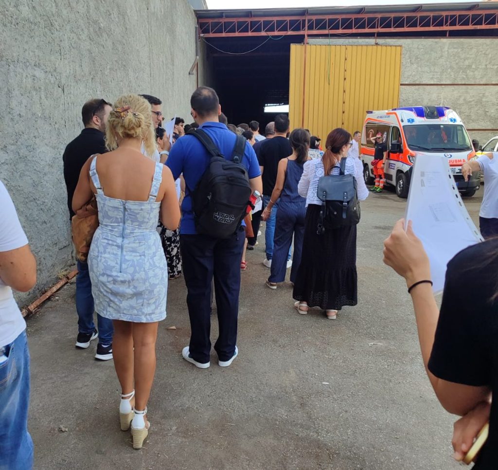 Candidati in coda con i fogli in mano davanti al capannone del PalaBova, con un'ambulanza sullo sfondo
