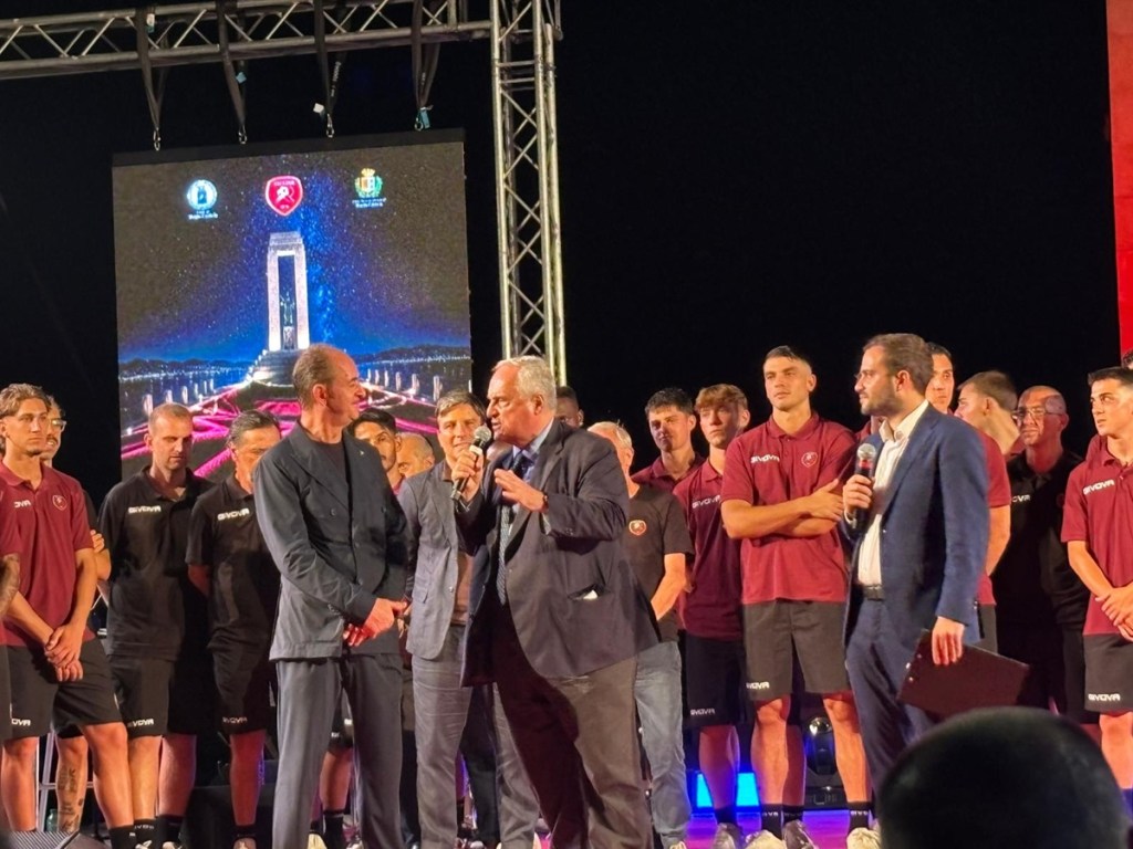Presentazione della Reggina con Lotito sul palco: un uomo parla al microfono davanti ai calciatori amaranto