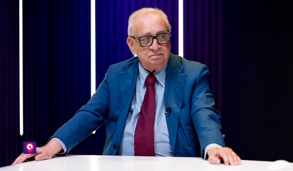 Gabriele Martino seduto in studio con le mani appoggiate al tavolo e lo sguardo rivolto di lato