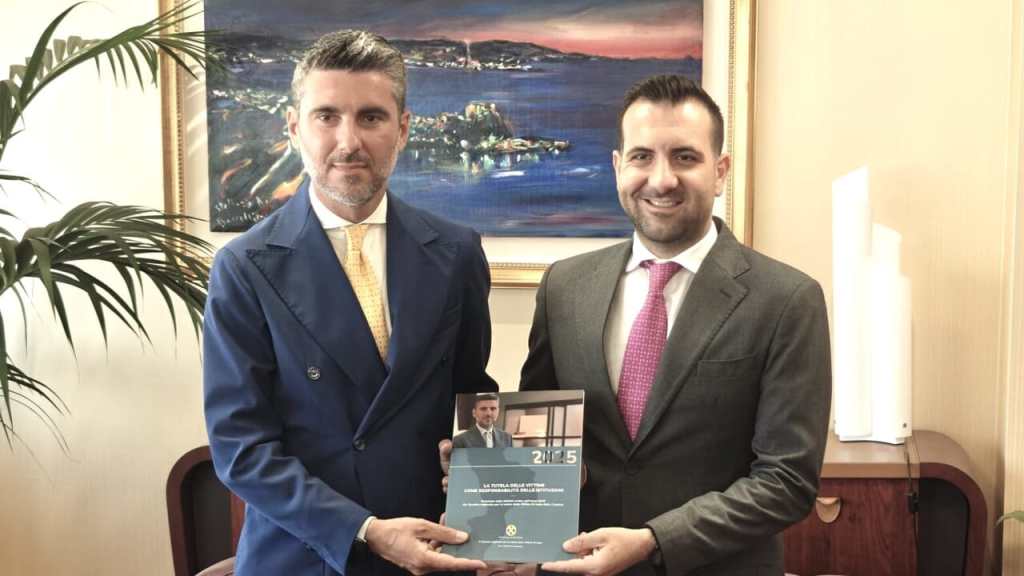 Antonio Lomonaco e Salvatore Cirillo posano in ufficio tenendo tra le mani una pubblicazione dedicata alla tutela delle vittime