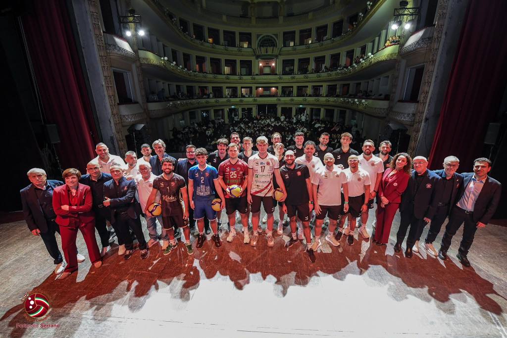 Atleti, staff e persone in abiti eleganti in posa sul palco del teatro, con la platea e i palchi sullo sfondo
